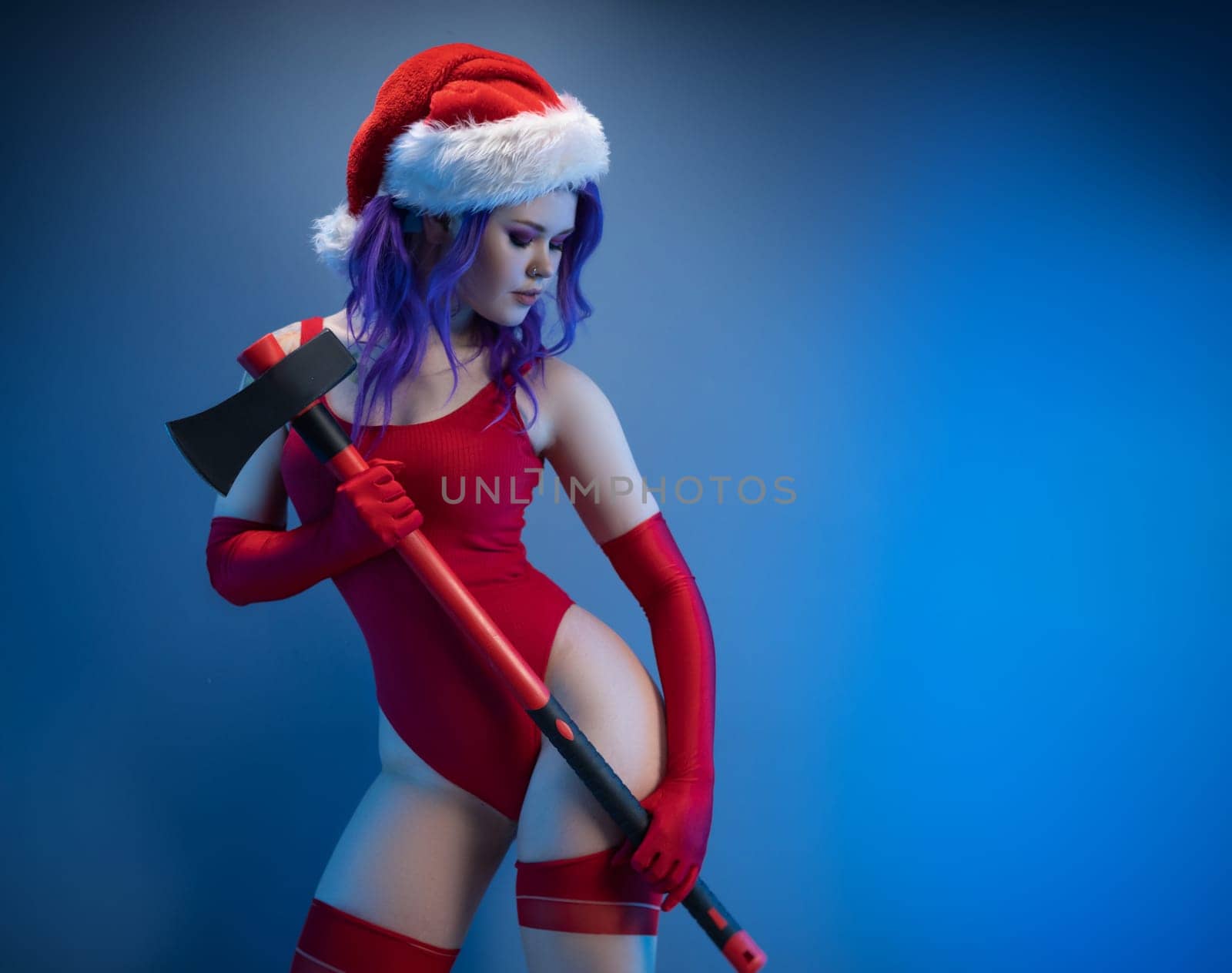 the sexy girl in red underwear and santa hat with an axe on a blue background