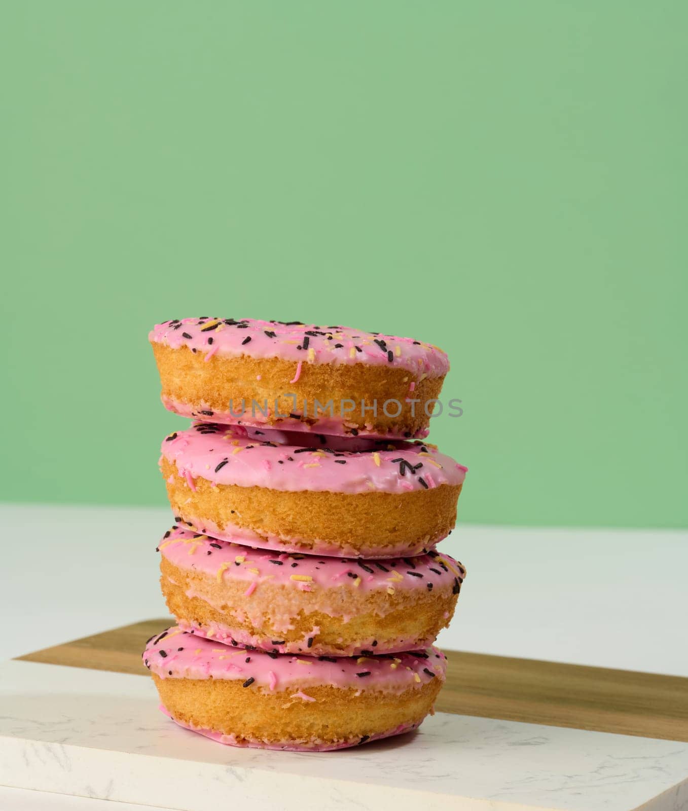 Donut covered with pink glaze and sprinkled with colorful sprinkles by ndanko