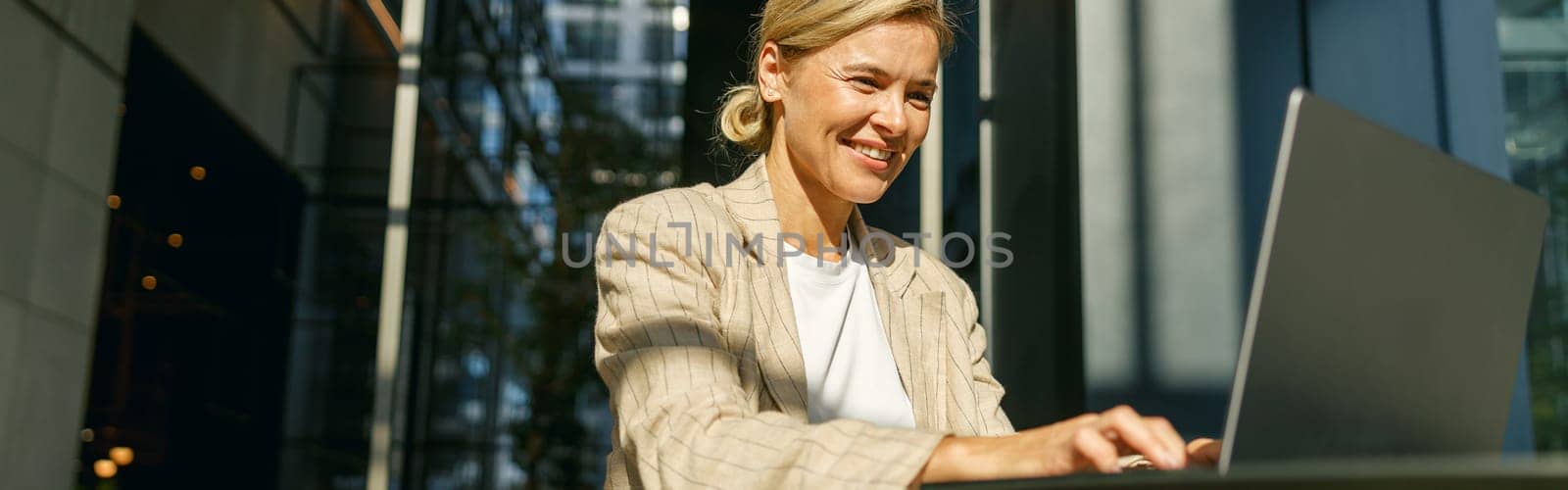 Smiling female sales manager working on laptop in modern coworking space