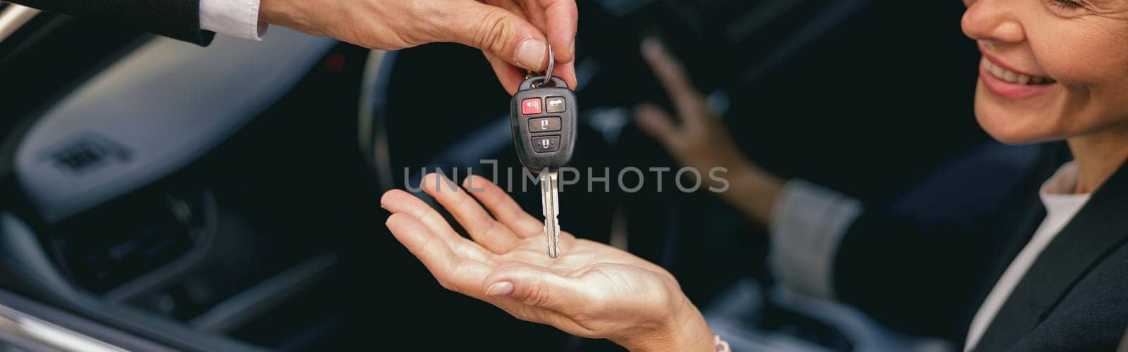 Close up of smiling business woman in suit receiving car keys to new vehicle by Yaroslav_astakhov