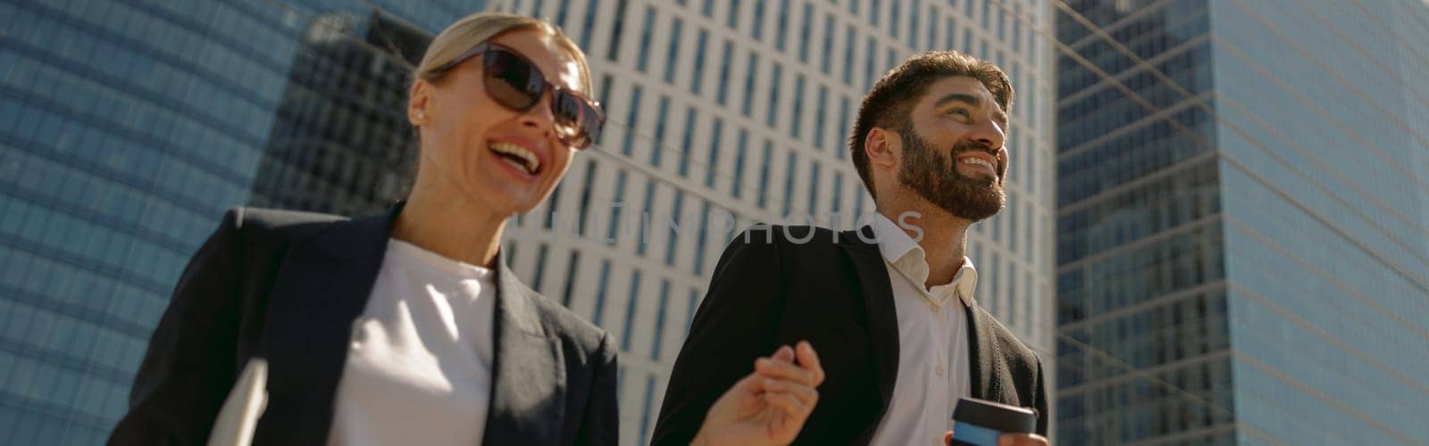 Business people talking during break time standing on background of modern city skyscrapers by Yaroslav_astakhov