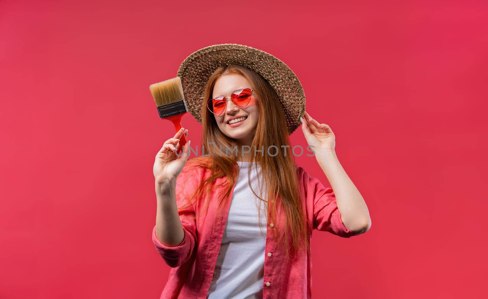 Young woman artist with brush on viva magenta or pink background. Creative person, fantasy, idea, non-standard approach to life. High quality photo