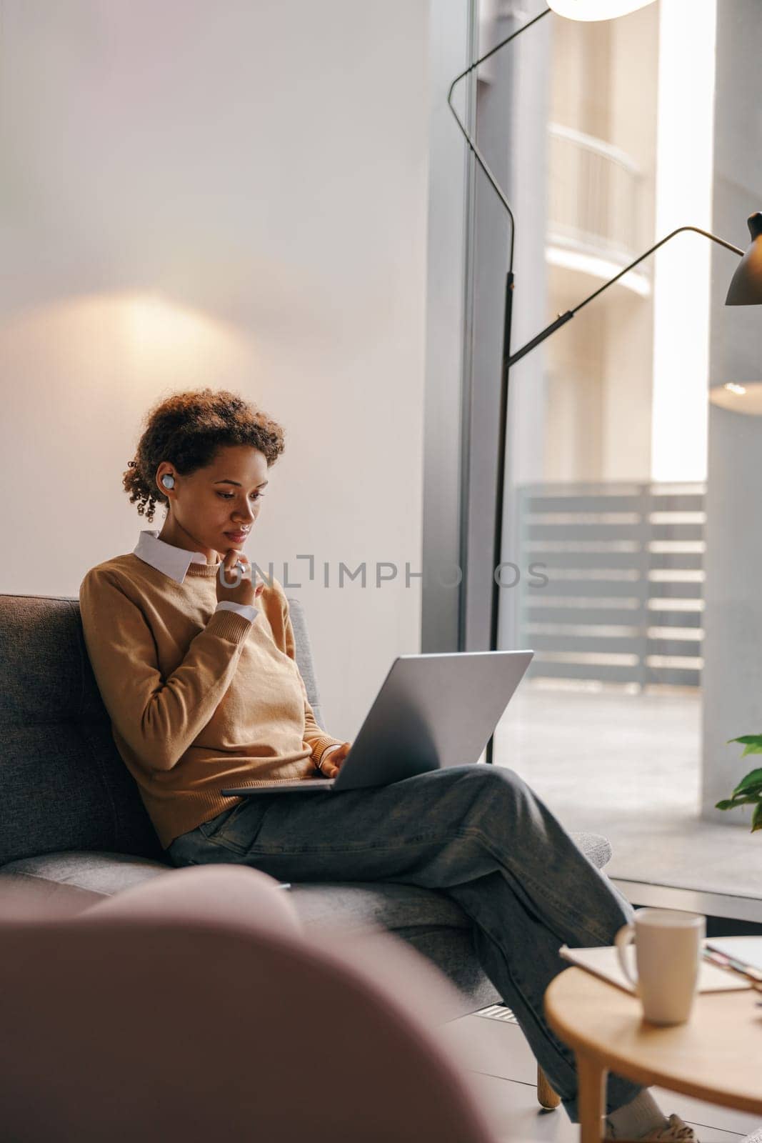 Business woman in eyeglasses working on laptop while sitting in modern office