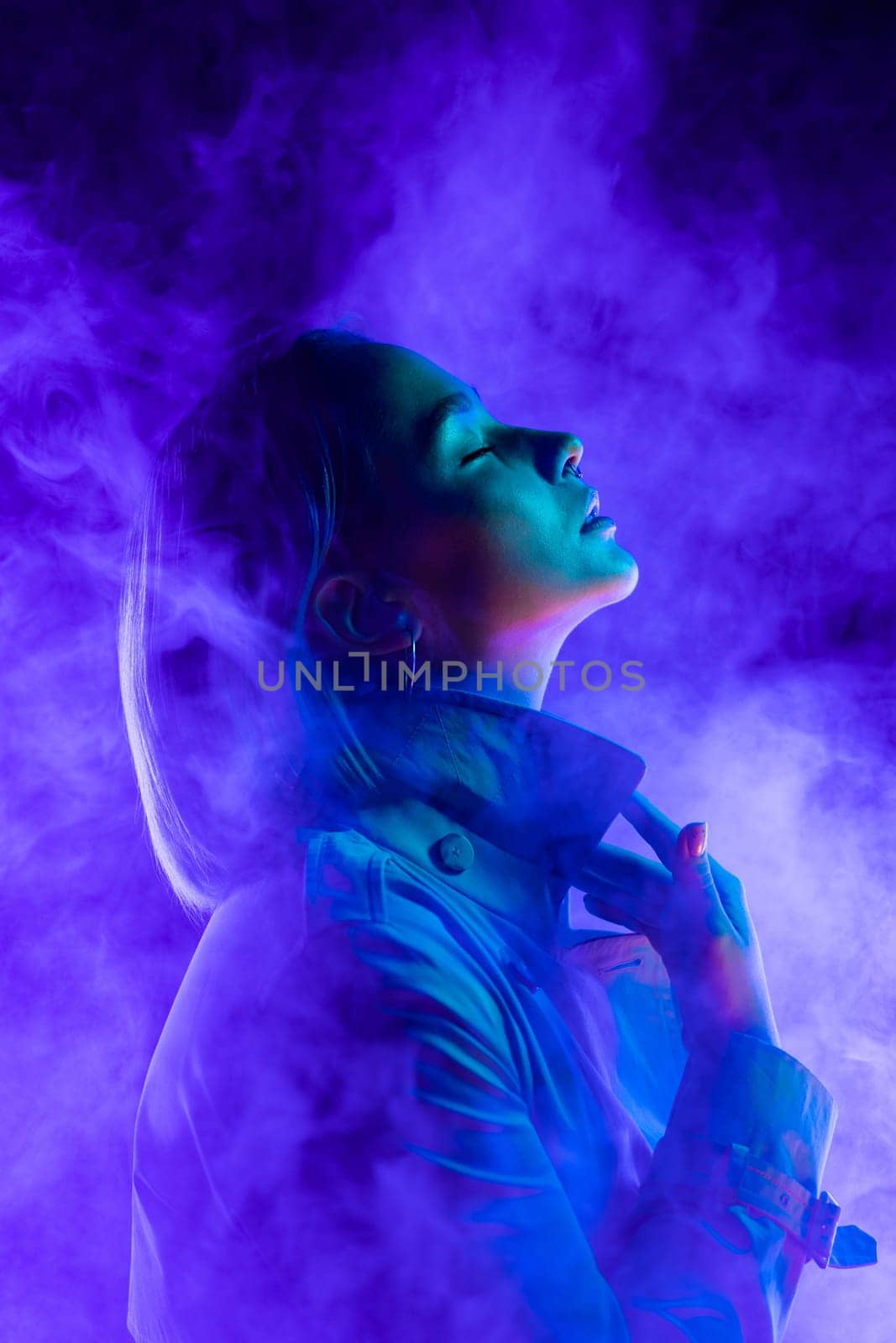 Young woman in neon multi-colors light on smoke, steaming background. stylish by kristina_kokhanova