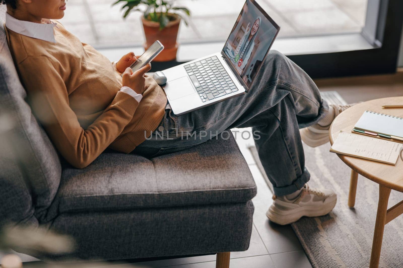Close up of female freelancer have video conference with client and use phone sitting in coworking by Yaroslav_astakhov