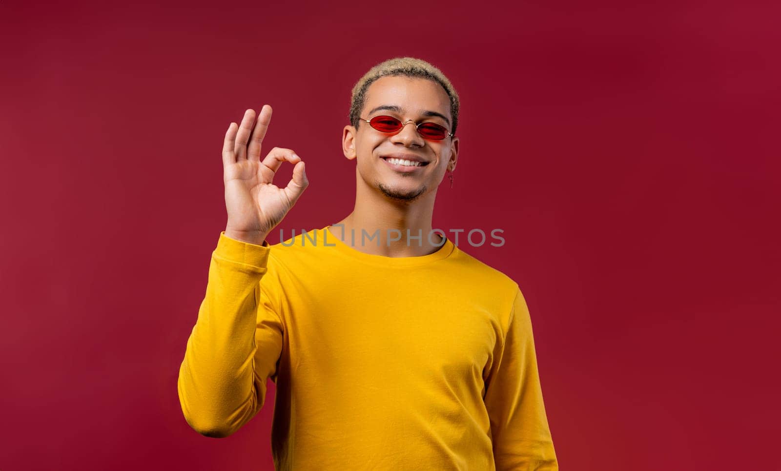 Positive man makes OK hand sign, okay gesture. Happy student guy in yellow by kristina_kokhanova