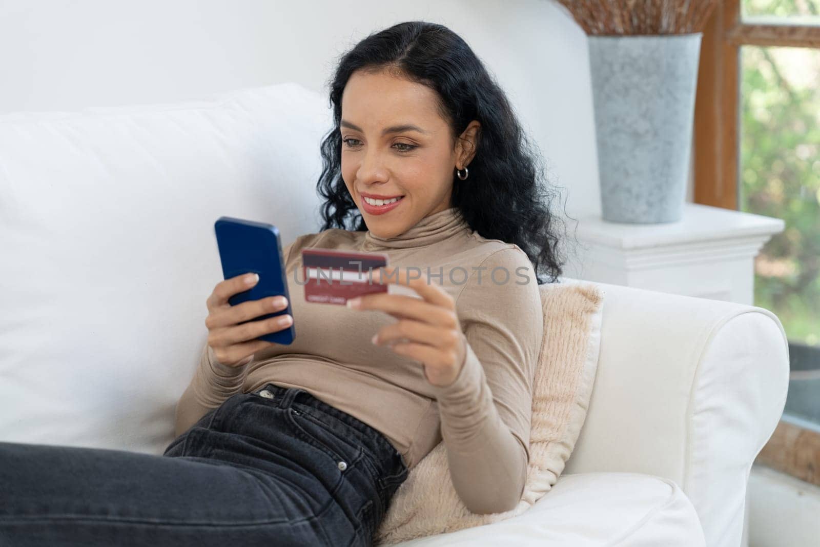 Young happy woman buy product by online shopping at home while ordering items from the internet with credit card online payment system protected by crucial cyber security from online store platform