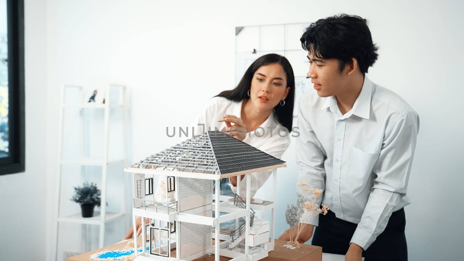 Closeup of young professional skilled architect engineer team focusing on checking the house model structure at modern office. Creative professional design and teamwork concept. Immaculate.