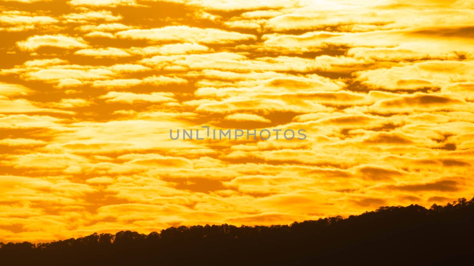 Time lapse of the beautiful sky with clouds at sunset. Sunset sky at dusk in the evening with natural sky background with golden orange clouds. by TEERASAK