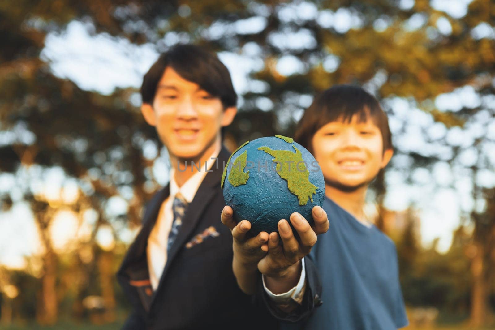 Focus Earth with blurred asian boy and businessman holding globe together. Gyre by biancoblue