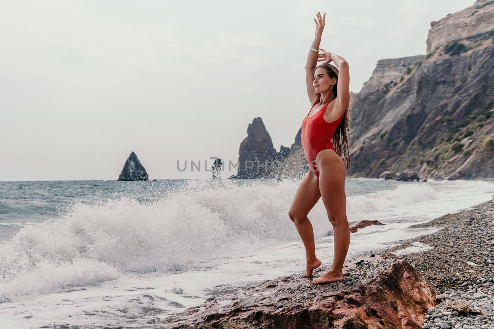 Woman summer travel sea. Happy tourist in red bikini enjoy taking picture outdoors for memories. Woman traveler posing on beach at sea surrounded by volcanic mountains, sharing travel adventure joy by panophotograph