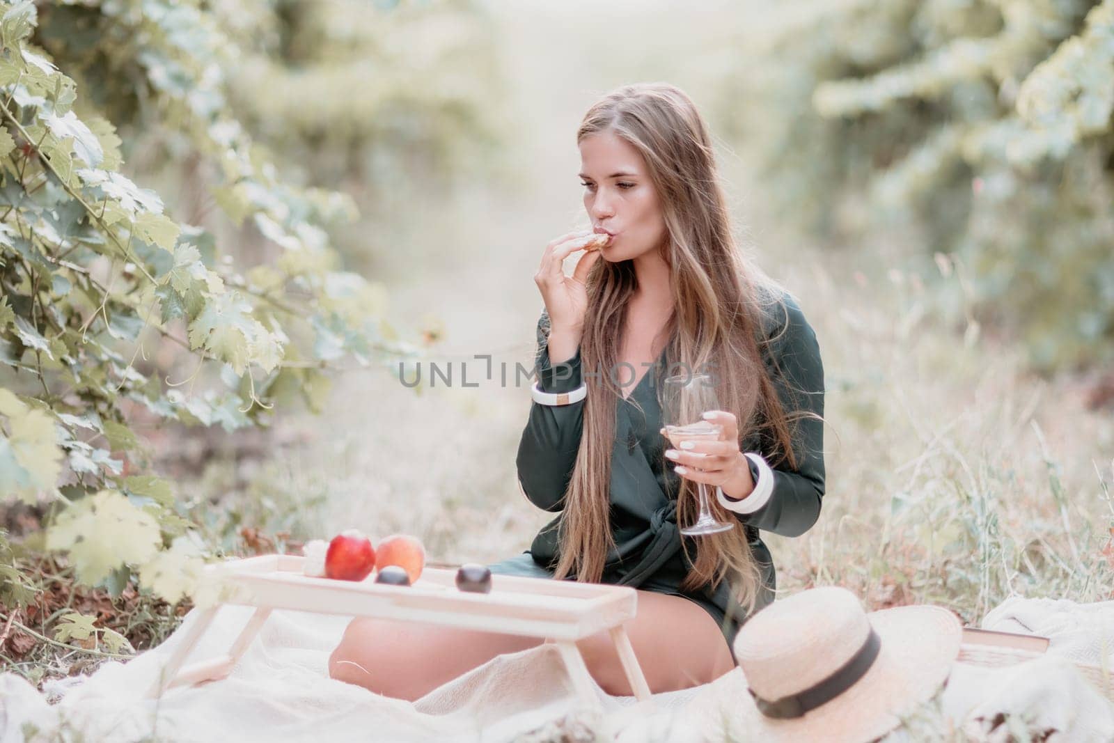 Woman picnic vineyard. Happy woman with a glass of wine at a picnic in the vineyard, wine tasting at sunset and open nature in the summer. Romantic dinner, fruit and wine. by panophotograph