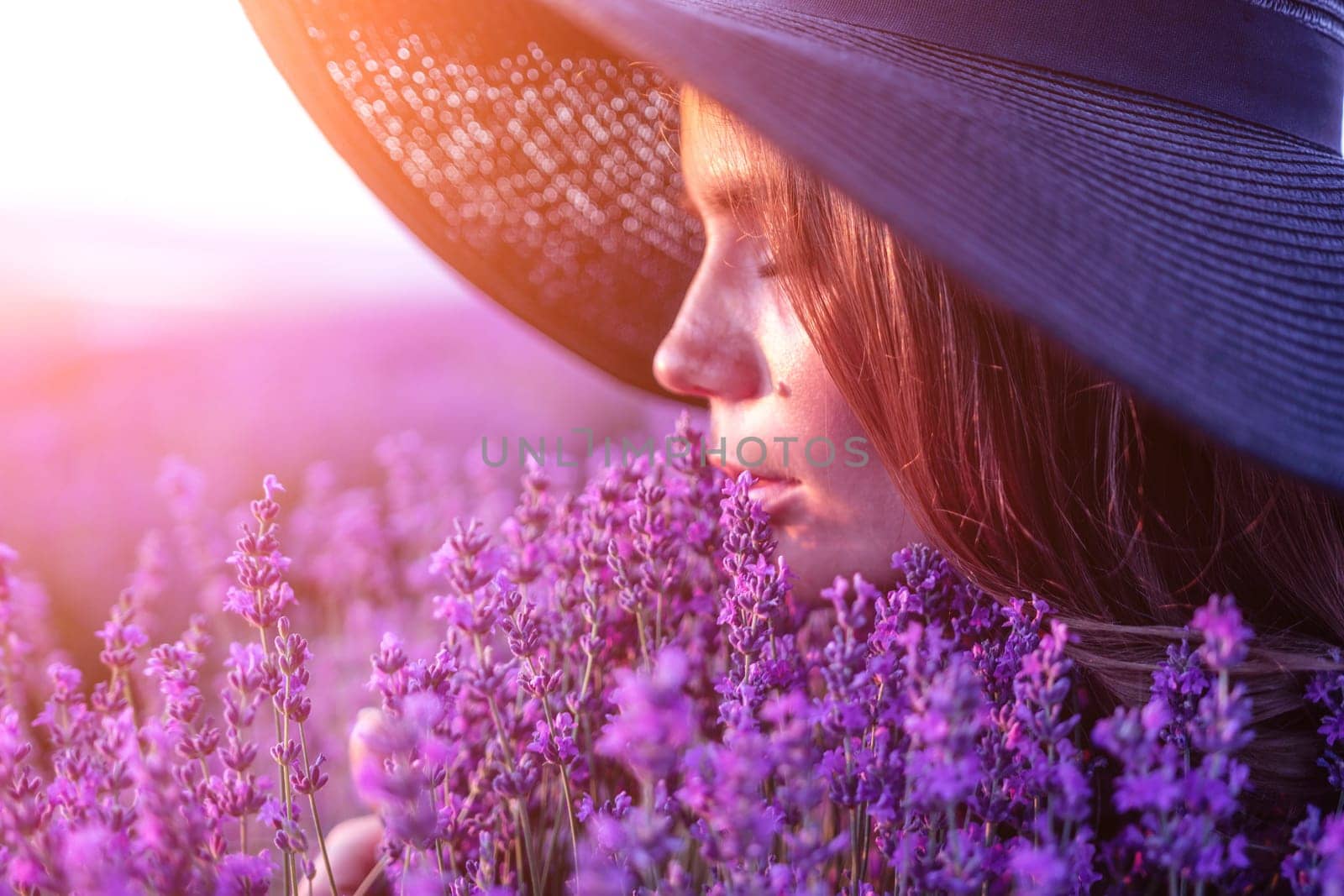 Woman lavender field. Happy carefree woman in black dress and hat with large brim smelling a blooming lavender on sunset. Perfect for inspirational and warm concepts in travel and wanderlust. Close up by panophotograph