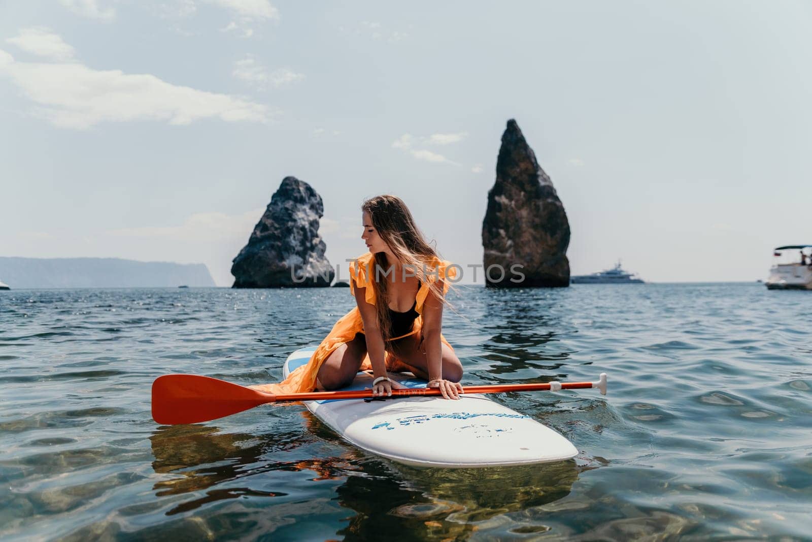 Woman sea sup. Close up portrait of happy young caucasian woman with long hair looking at camera and smiling. Cute woman portrait in bikini posing on sup board in the sea by panophotograph