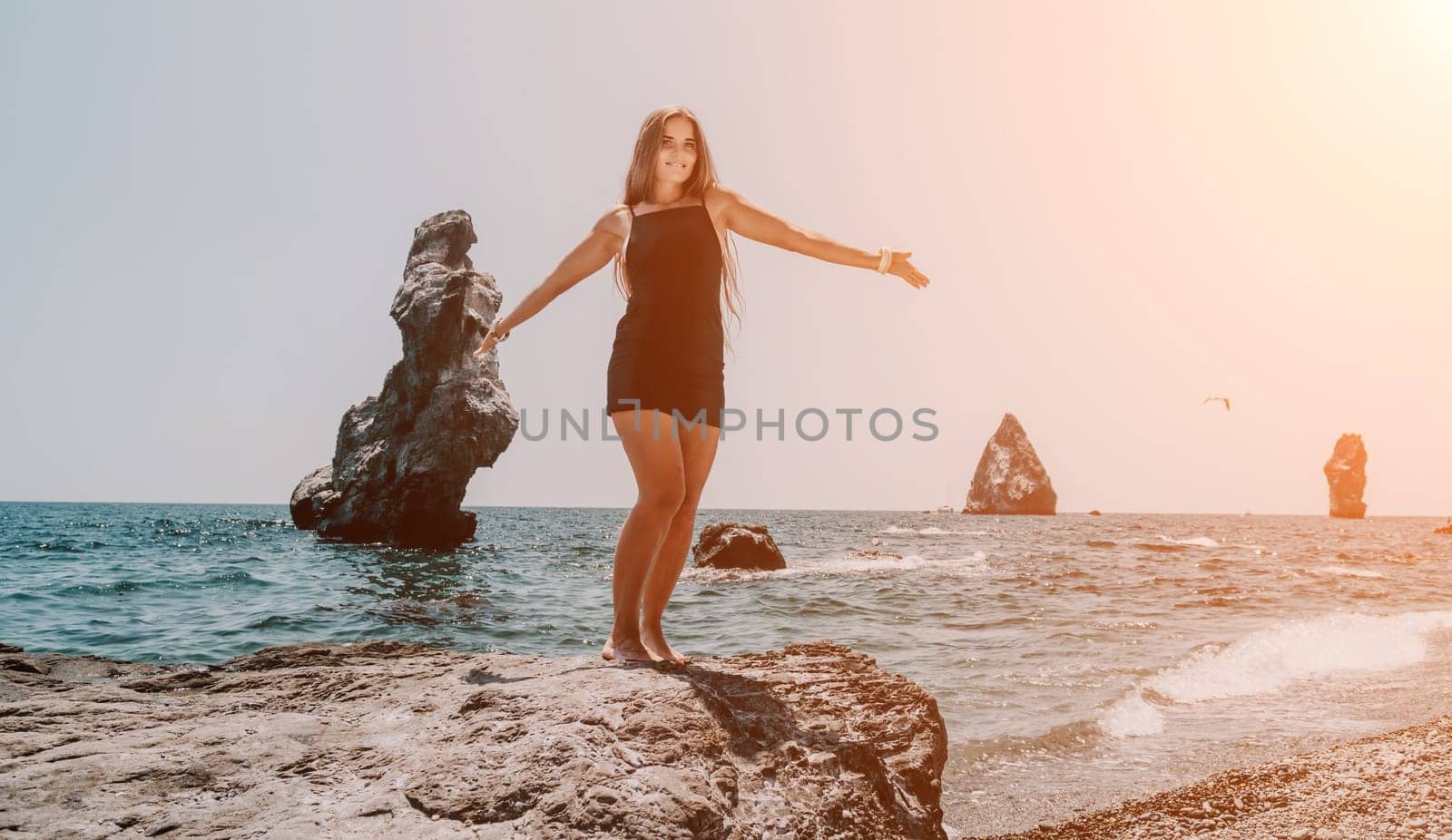 Woman summer travel sea. Happy tourist in hat enjoy taking picture outdoors for memories. Woman traveler posing on the beach at sea surrounded by volcanic mountains, sharing travel adventure journey by panophotograph