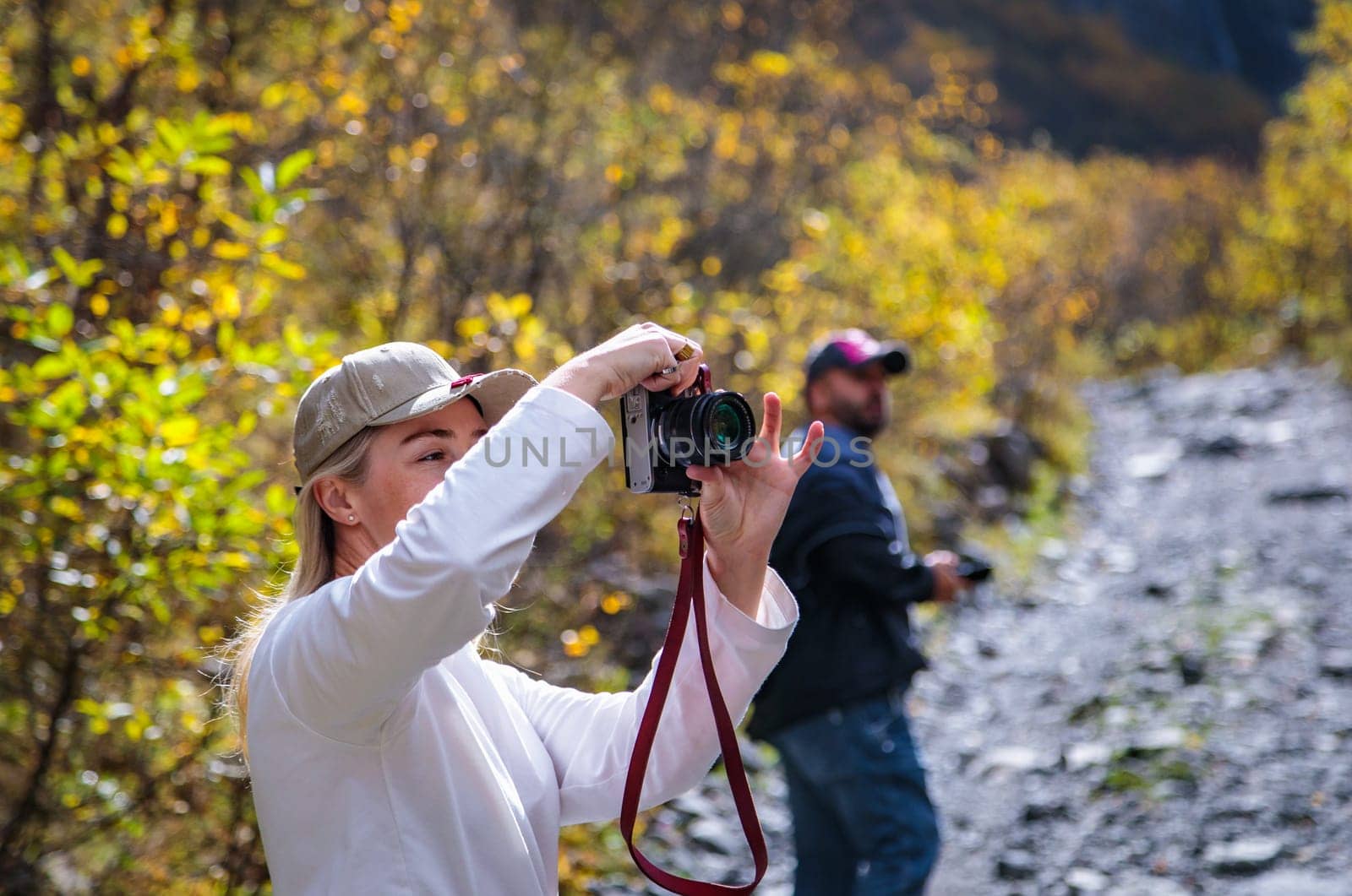 Young woman taking pictures of beautiful mountains with camera, majesty of nature and photography