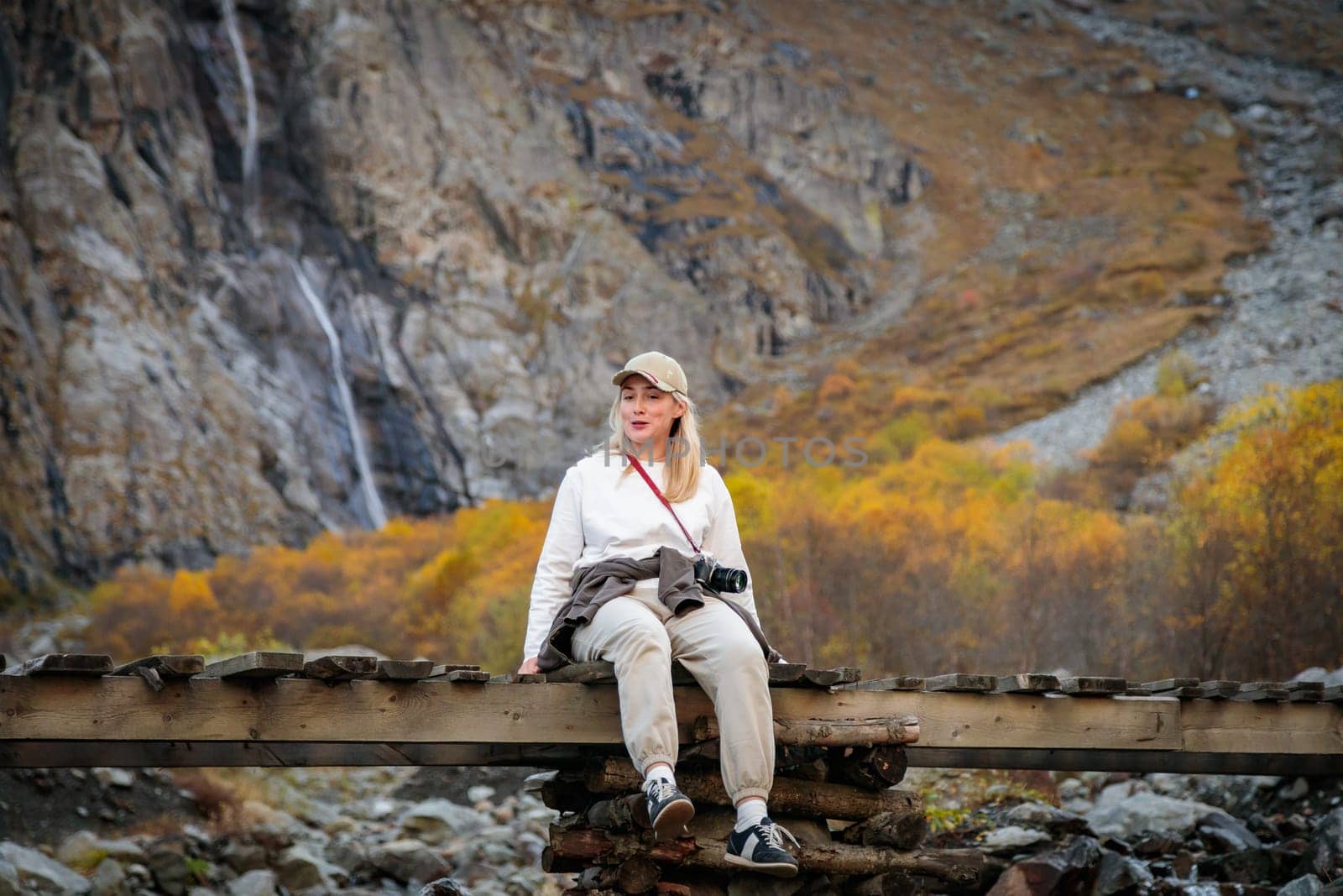 Solitude with nature, girl contemplating a majestic waterfall while sitting on a bridge