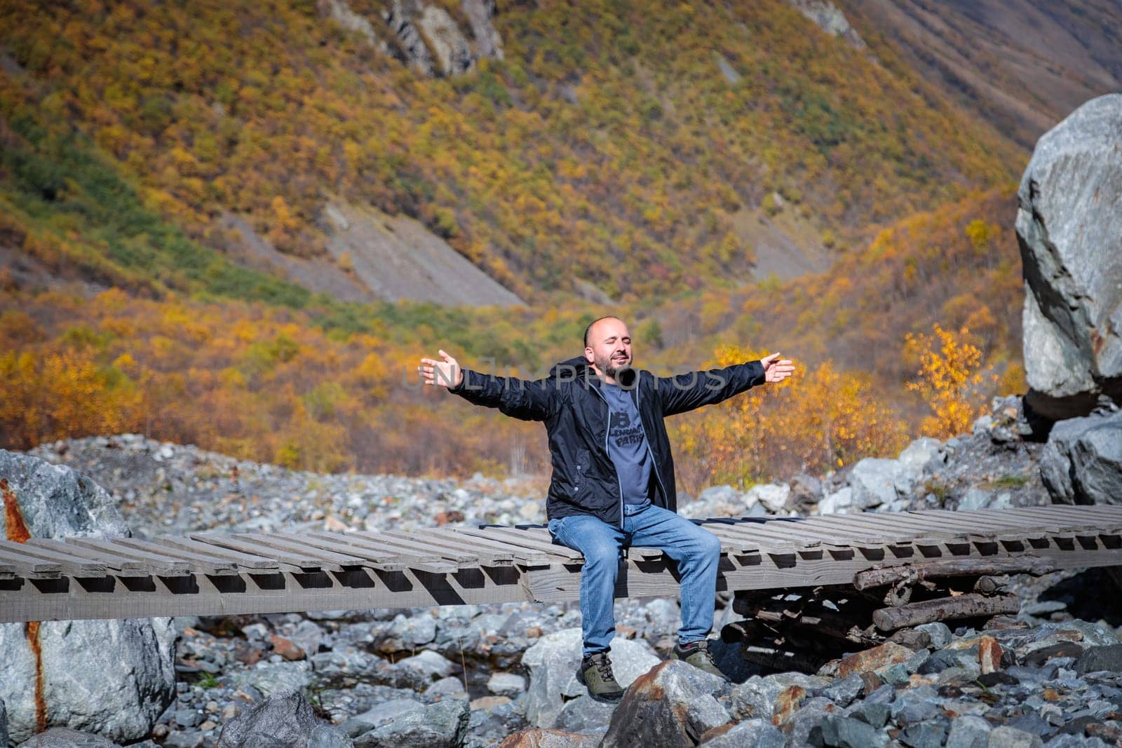 Man enjoying nature while sitting on bridge in mountains by Yurich32