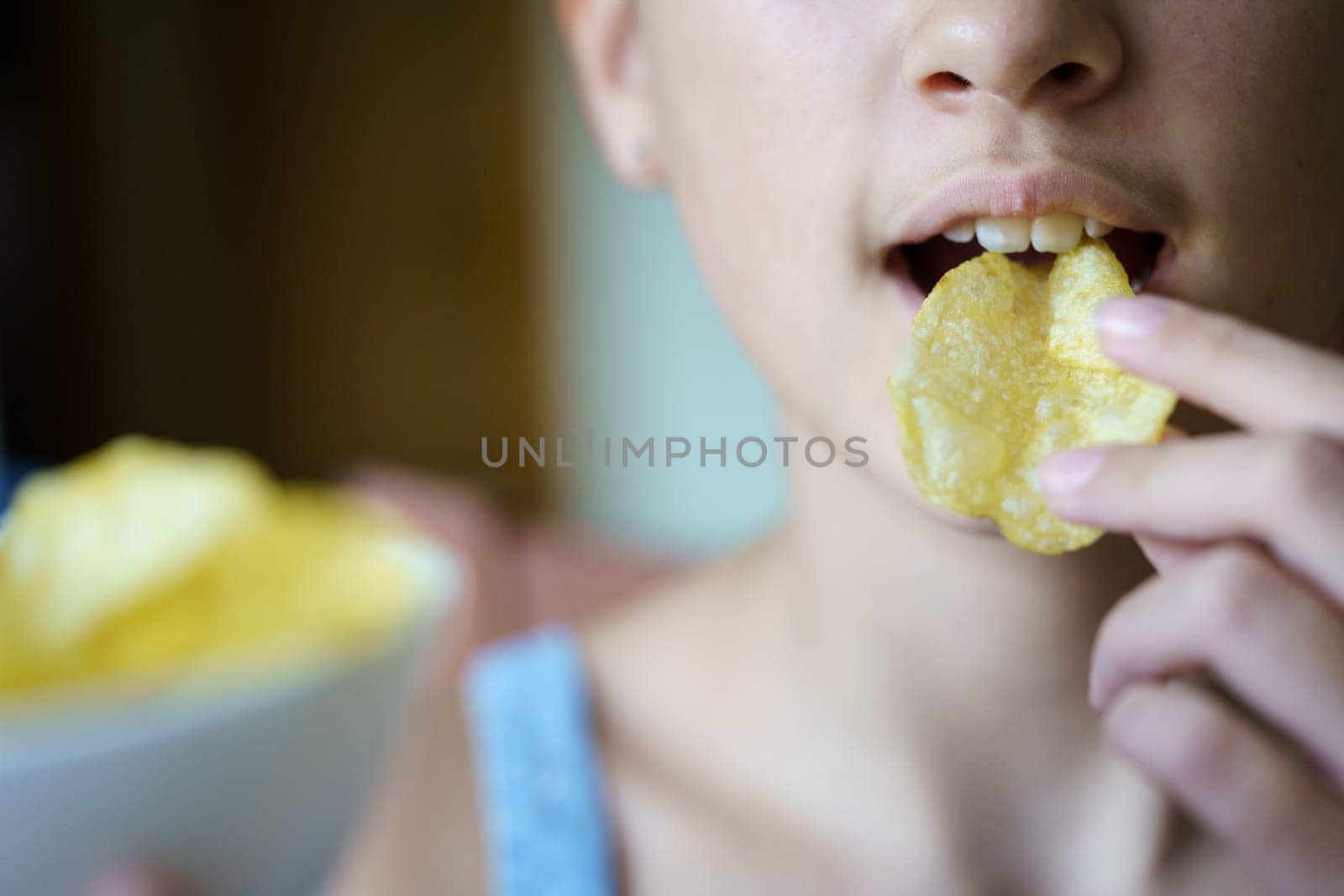 Unrecognizable young girl eating crispy potato chip by javiindy