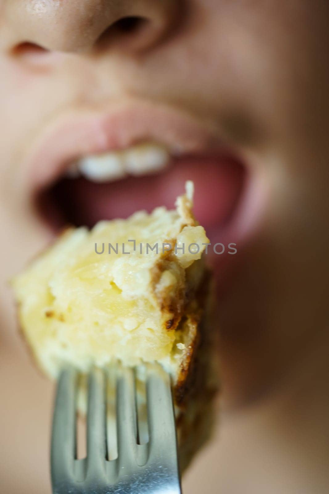 Closeup of crop anonymous young girl about to eat delicious potato omelette from fork at home