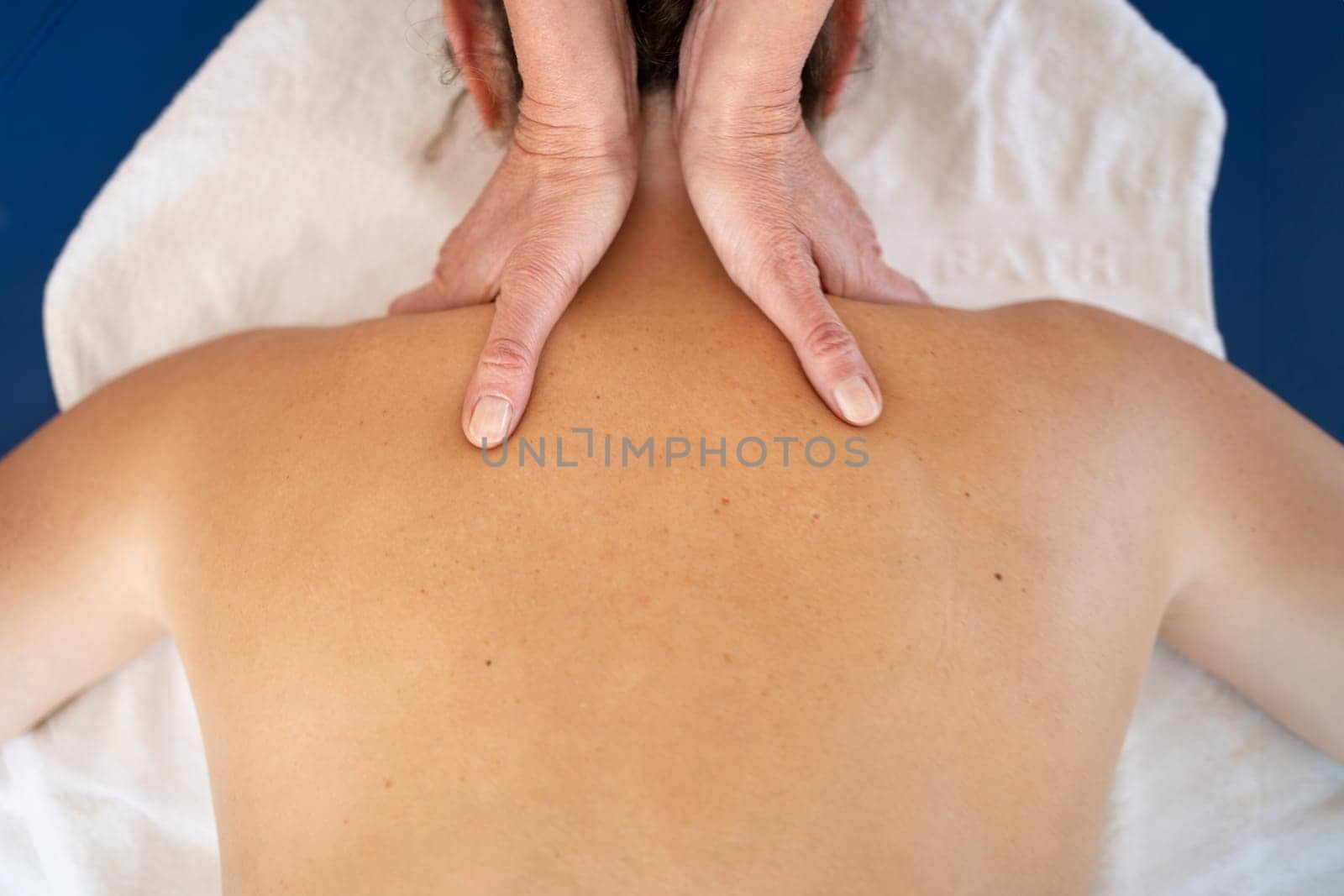Masseuse kneading shoulders of woman in spa salon by javiindy