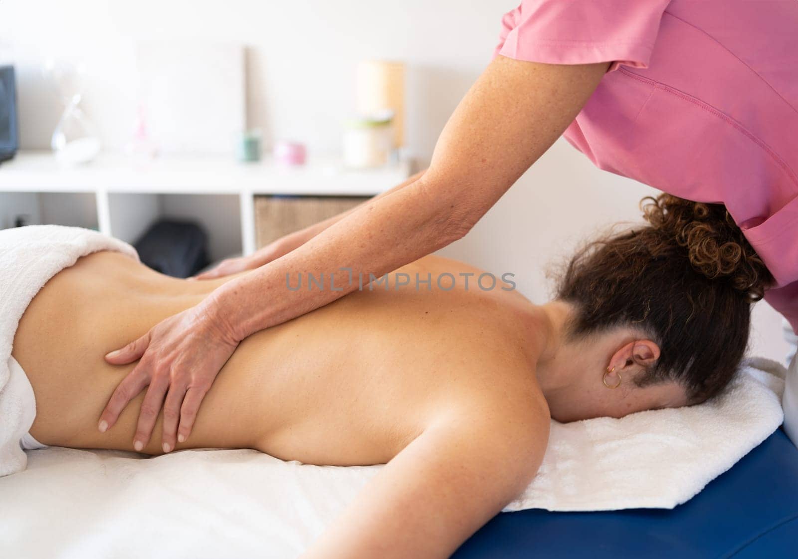 Masseuse rubbing back of woman in spa salon by javiindy
