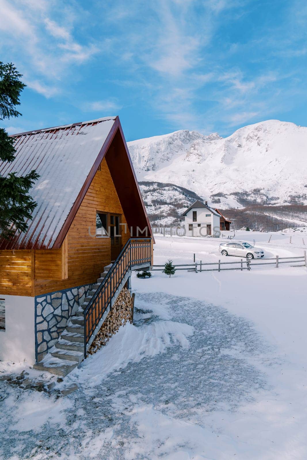 Wooden snow-covered two-story cottage in a small village in a mountain valley. High quality photo