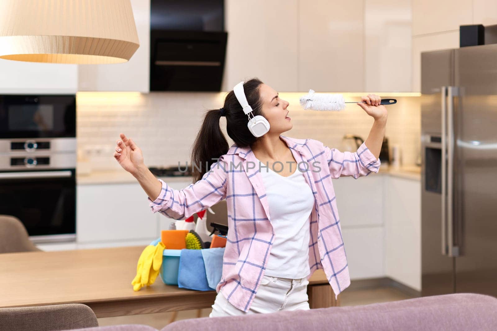 young happy housewife woman singing and cleaning her home, girl enjoying domestic work.