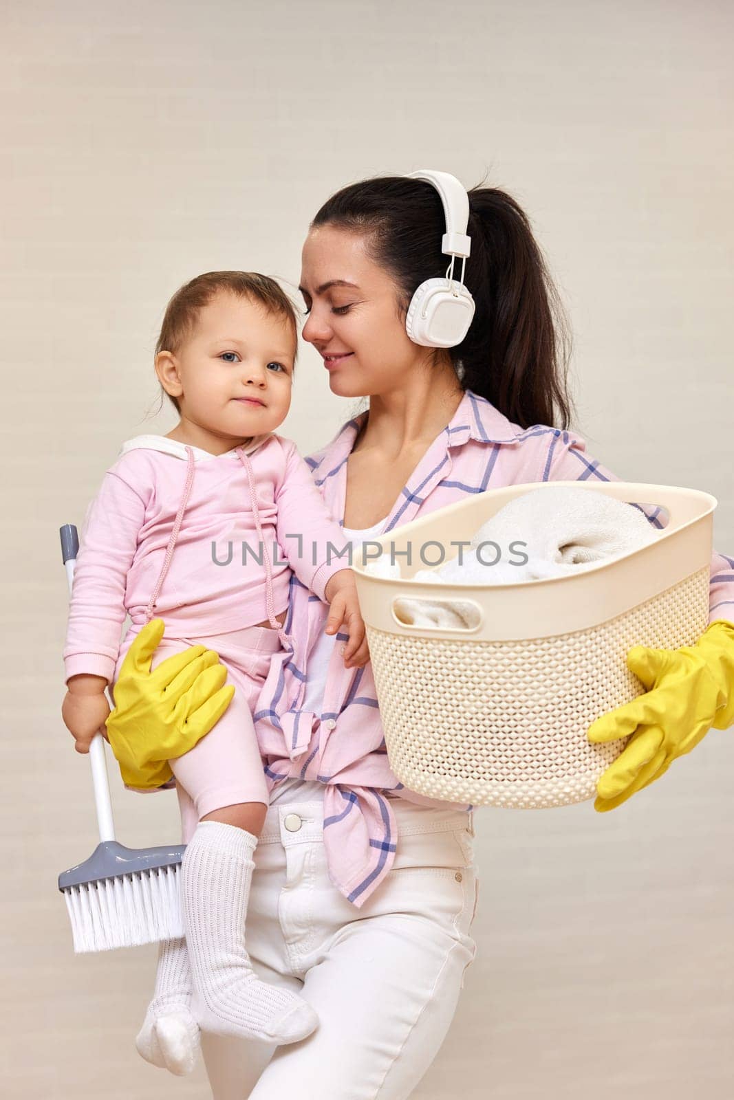 happy mother housewife is holding cute little child girl and basket with laundry , Happy family