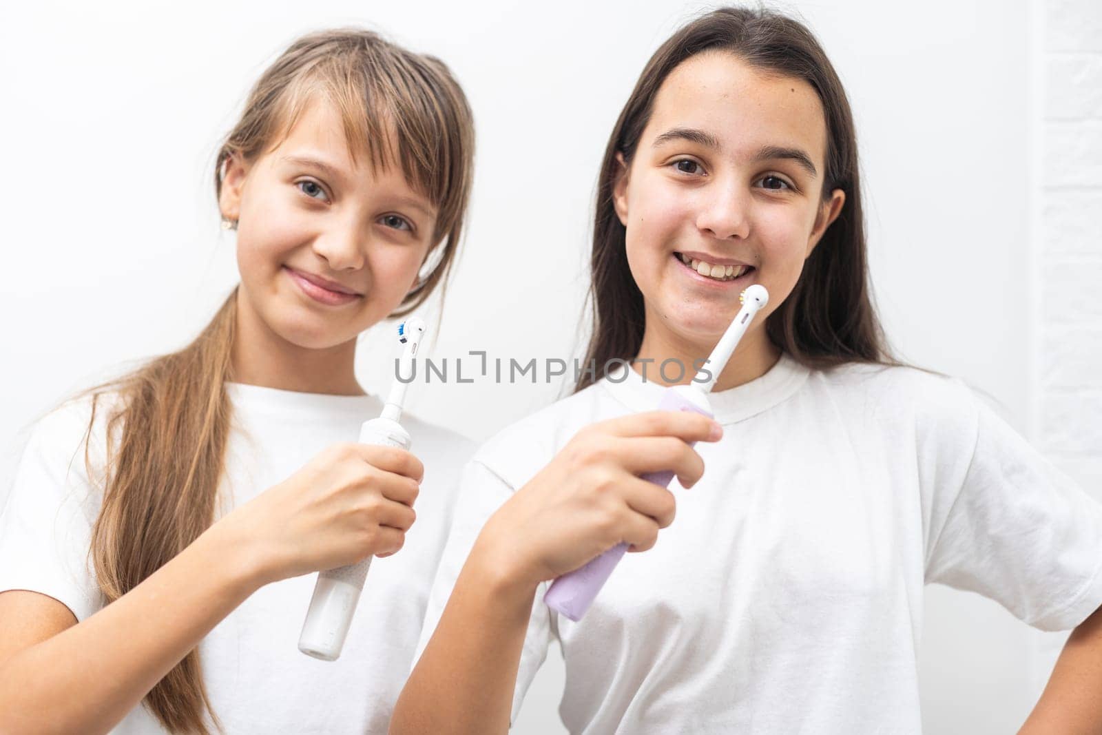 Portrait of two beautiful girls kids with perfect smile holding toothbrushes. Child dental care, oral hygiene concept. High quality photo