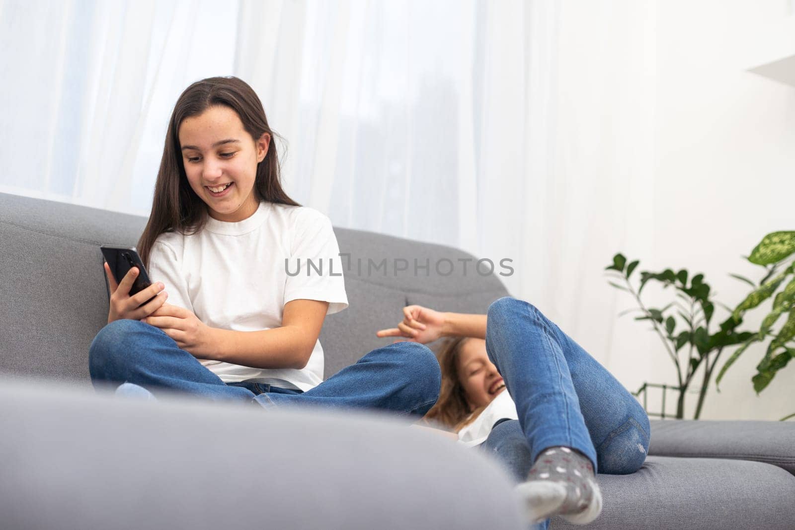 Happy schoolgirl lying near her friend and using new smartphone for chat. High quality photo