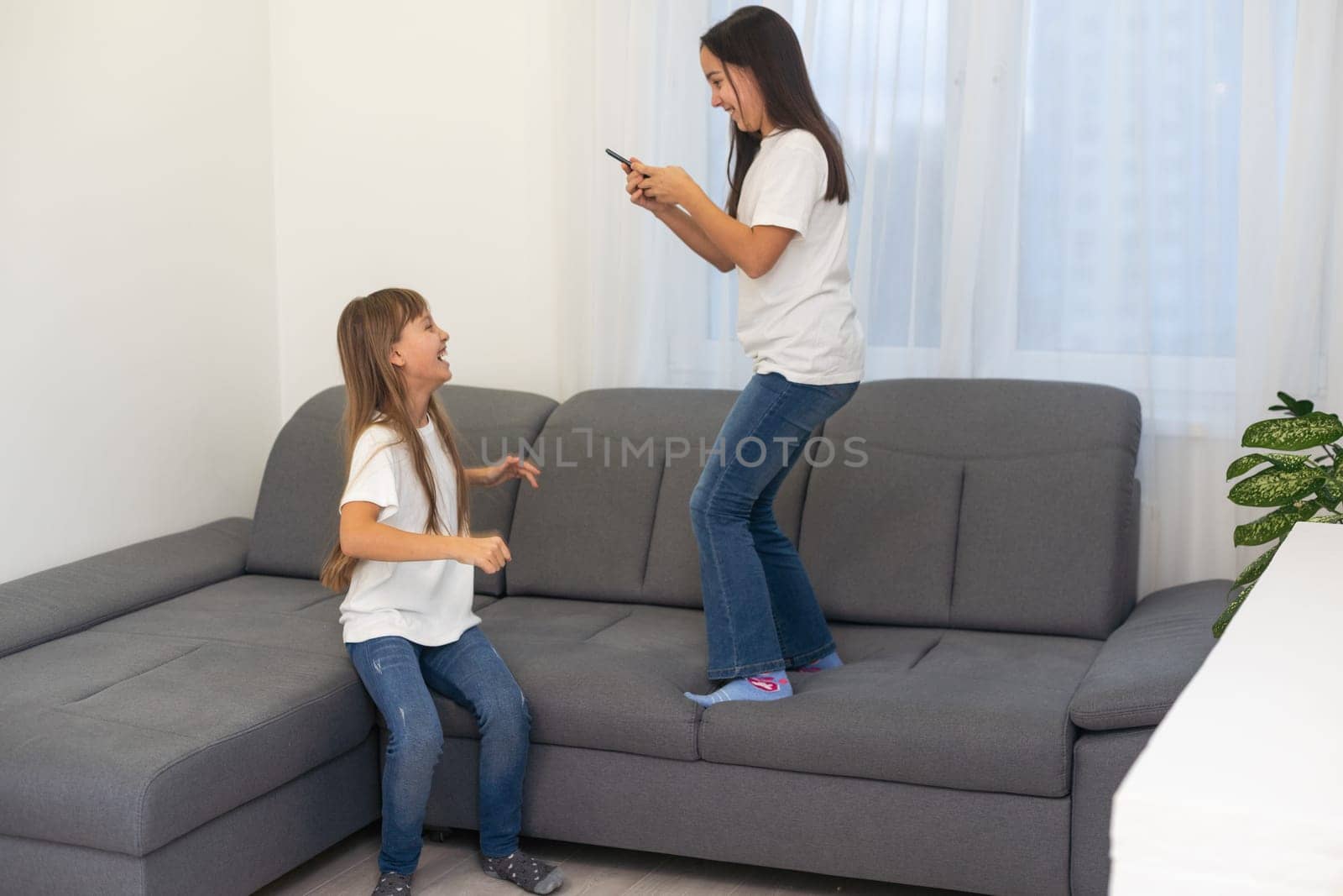 people, technology and friendship concept - happy teenage girls taking selfie with smartphone sitting on sofa at home by Andelov13