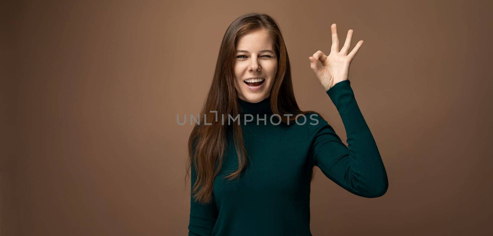 Attractive young woman with healthy brown hair showing ok and class gesture by TRMK