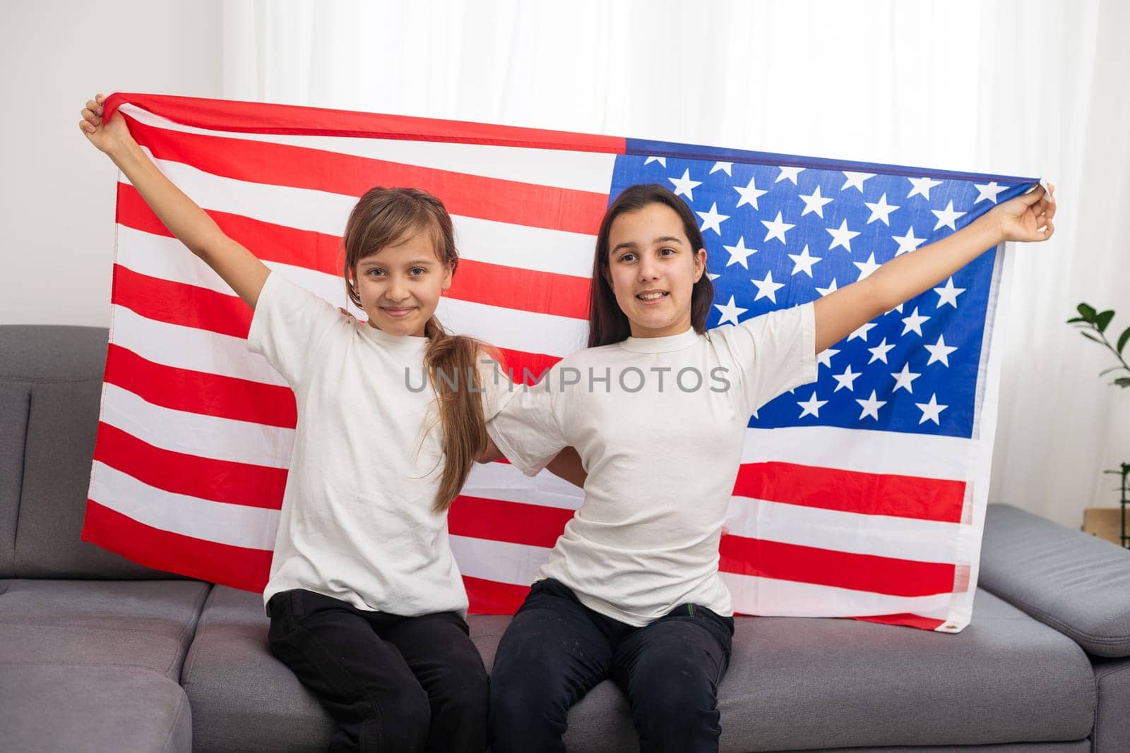Two sisters with American flag on grey background. High quality photo