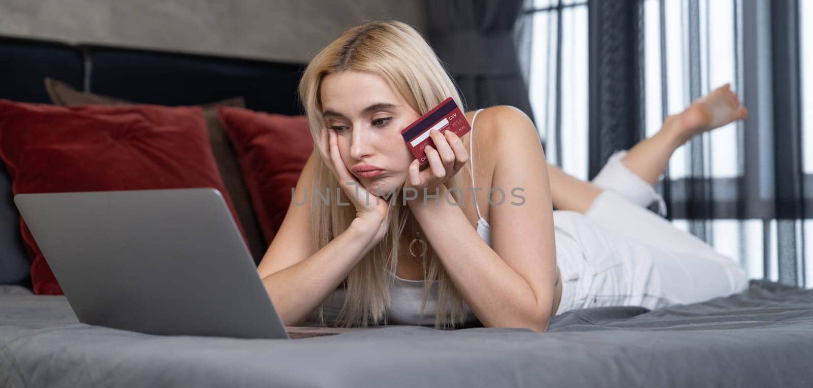 Stress worried young woman sit at table, as she pay bills online with credit card from financial debt problem, monthly expense and credit card debt. Over spending money problem. Panorama Blithe