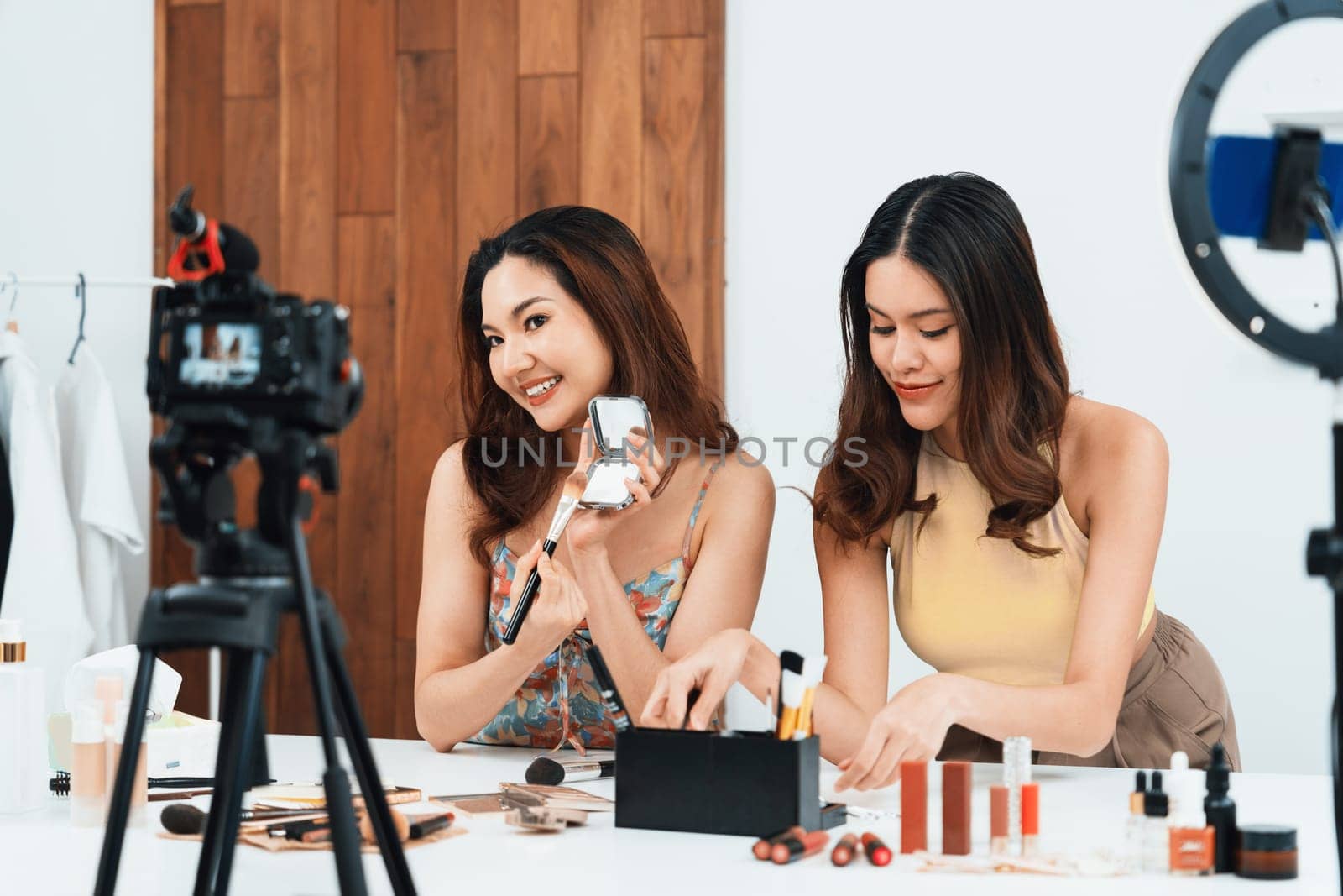 Asian Woman influencer shoot live streaming vlog video review makeup uttermost social media or blog. Happy young girl with cosmetics studio lighting for marketing recording session broadcasting online