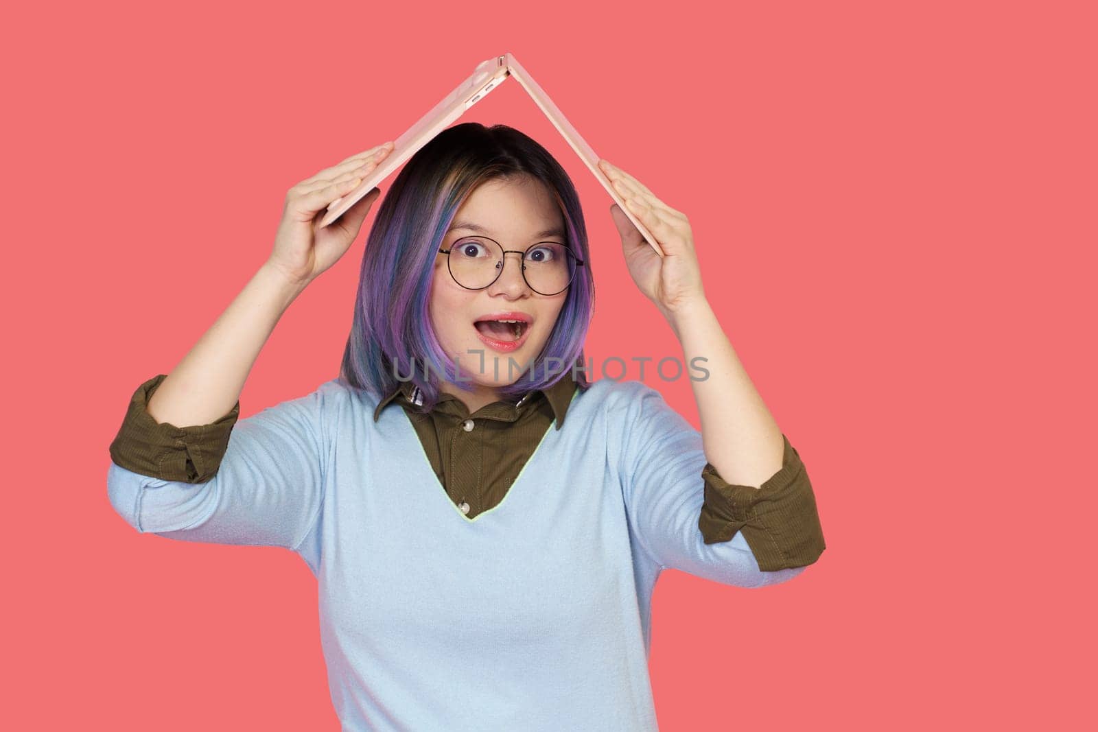 Teenager girl covering her head with unfolded laptop, forming protective roof symbolizes safeguarding of knowledge. Concept being smart and seeking education for secure and enlightened future. High quality photo