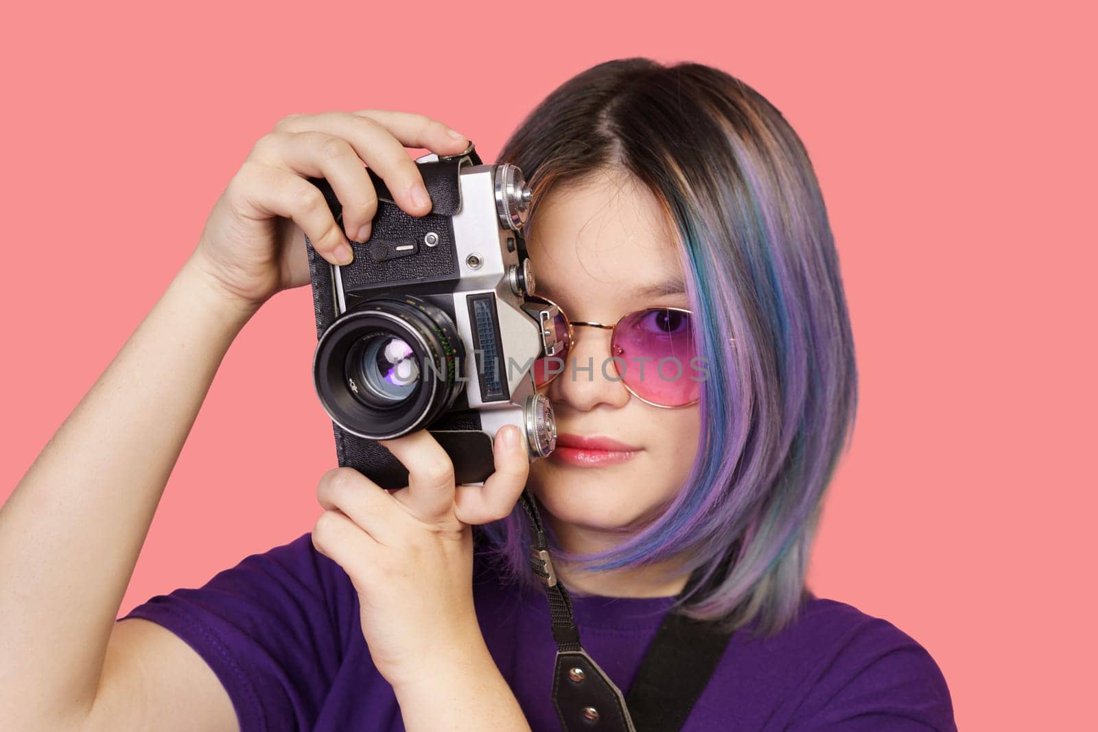 Teenager asian girl with old school photo camera against vibrant pink background. Youthful enthusiasm for photography, combining modern era with vintage charm of analog camera. close-up portrait by LipikStockMedia