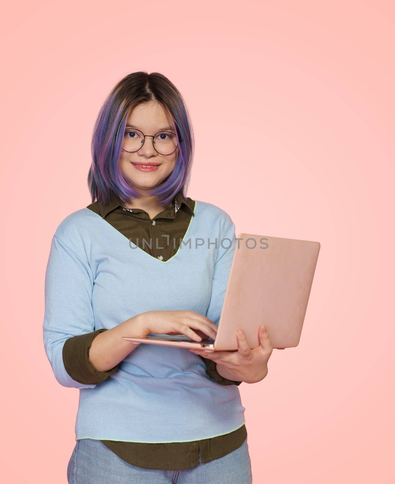 Friendly female student with laptop smiles against cheerful pink background. Dedicated and motivated student who excels in studies, creating vision of success and achievement in educational journey. High quality photo