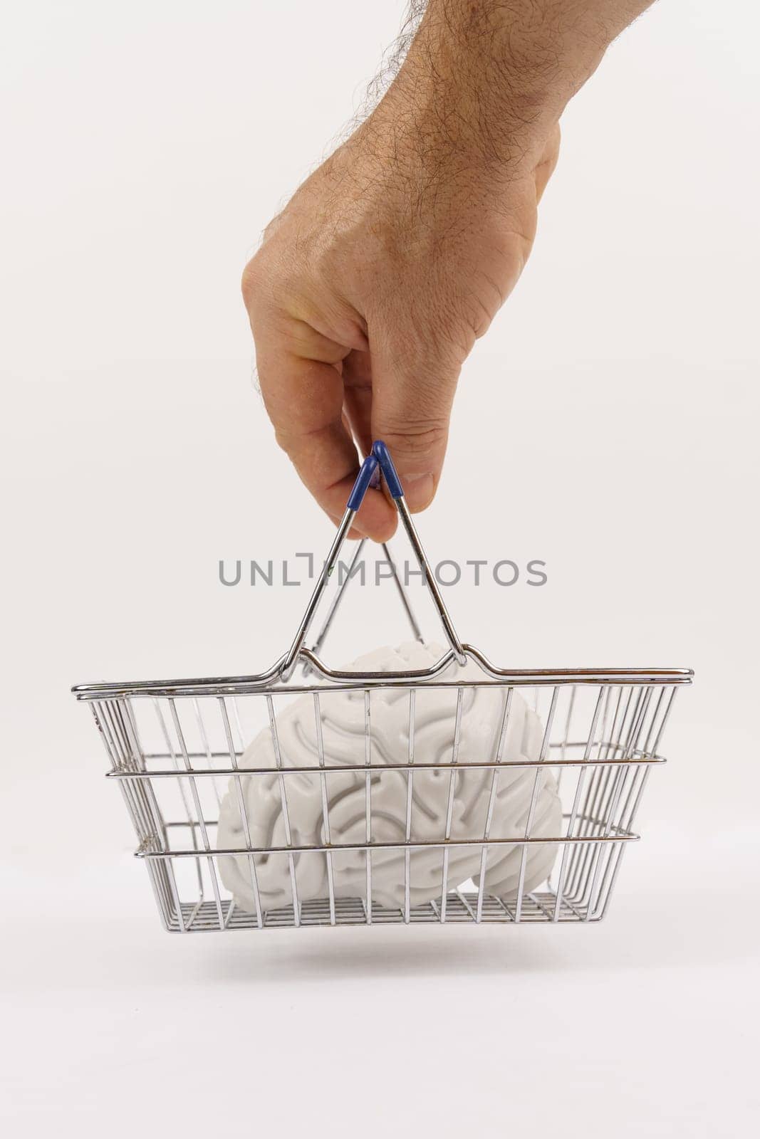 A man's hand holds a shopping basket with a human brain inside. Image on a white background. Vertical frame