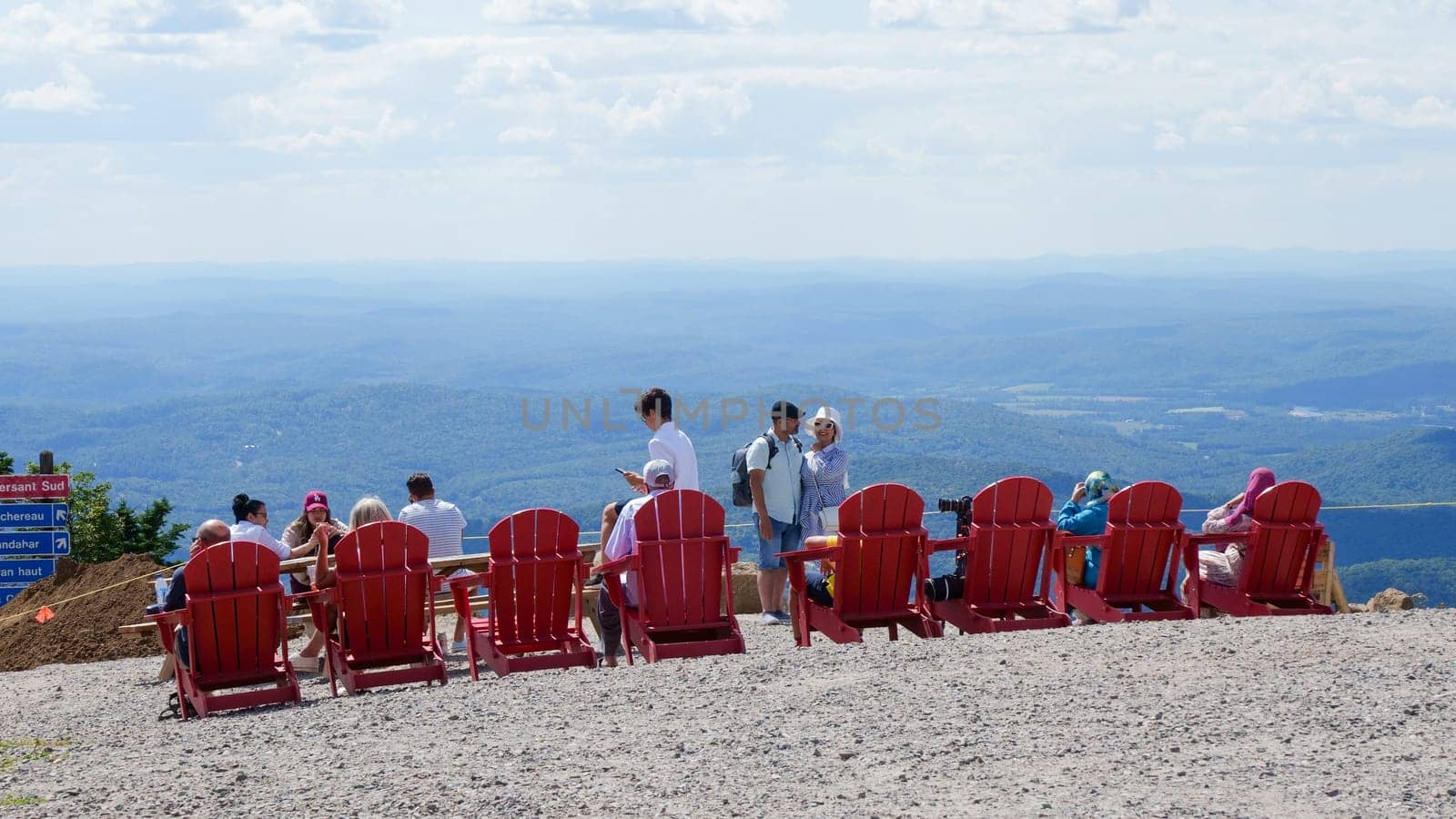 Sightseeing mountain views at Mont Tremblant ski Resort in summer. Tourists enjoying sitting at red chairs at ski resort village. Mont-Tremblant, Quebec, Canada - 22.09.2022 by JuliaDorian