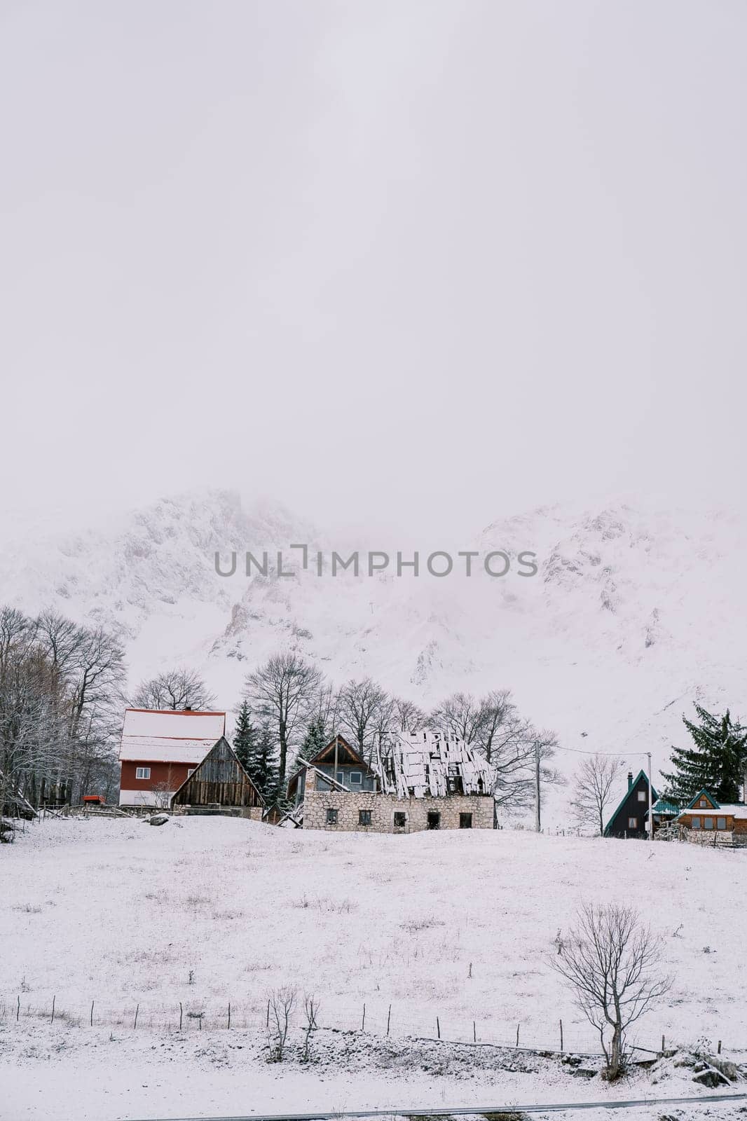 Snow-covered house under construction in a small village at the foot of the mountains. High quality photo