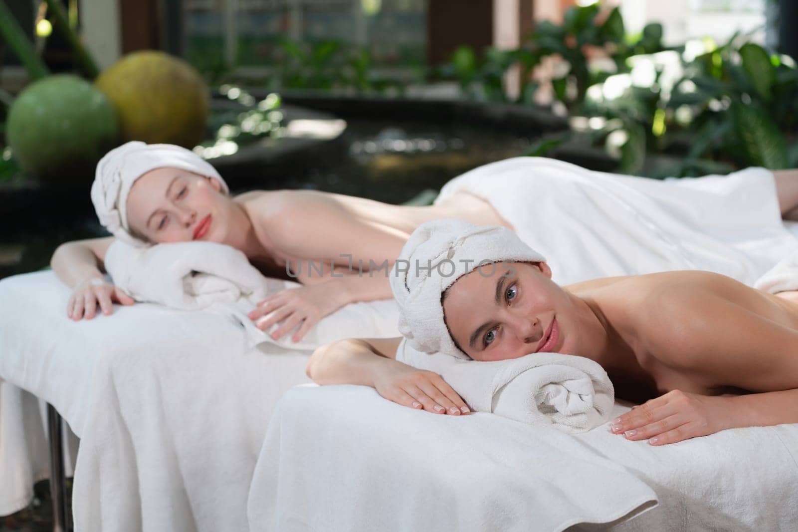A portrait of a couple of attractive young woman lie on spa bed. Tranquility. by biancoblue