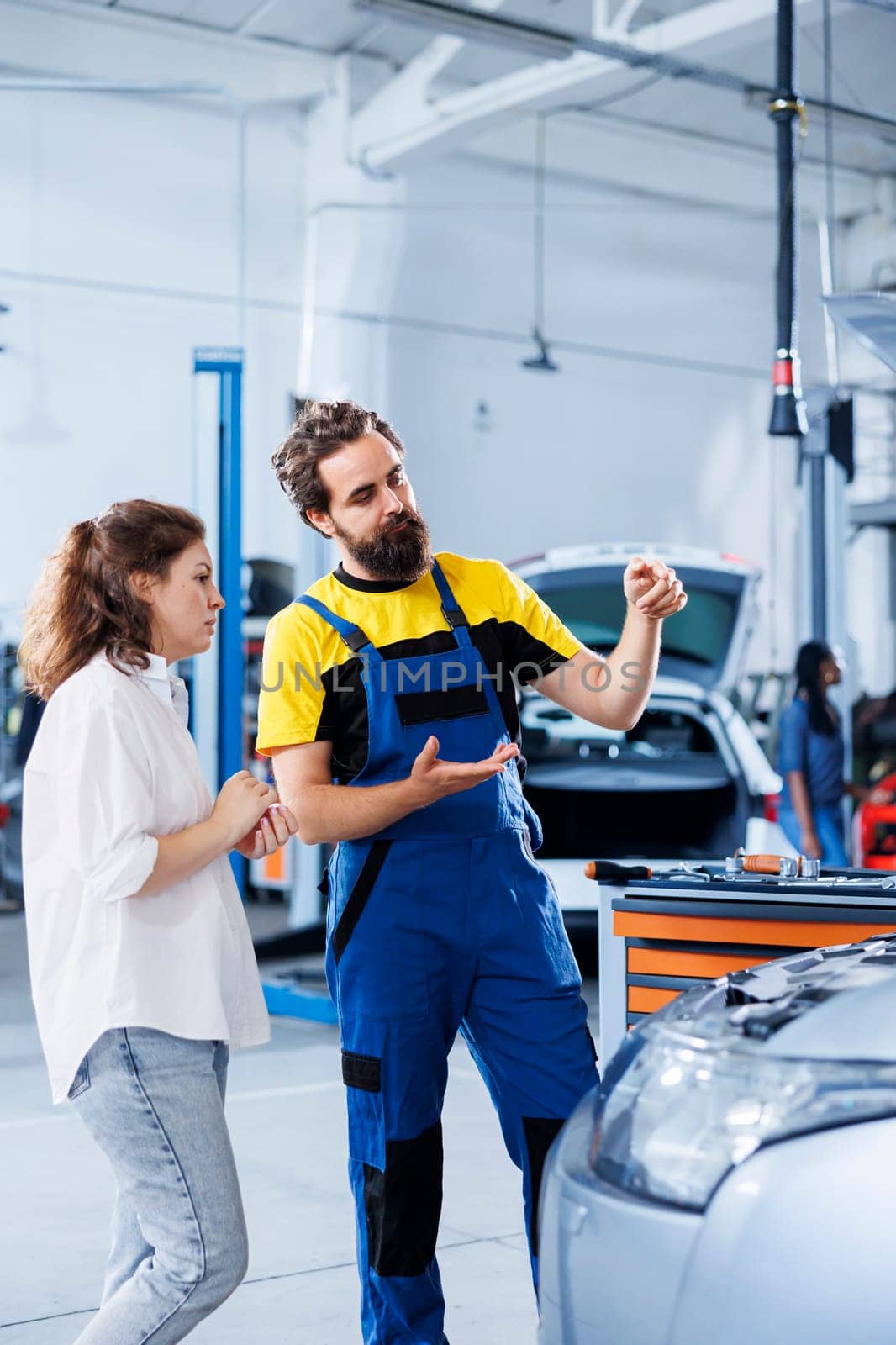 Adept repairman in repair shop using holographic AR technology to show customer car performance parameters. Garage worker using futuristic vr headset to inform client of issues found in vehicle