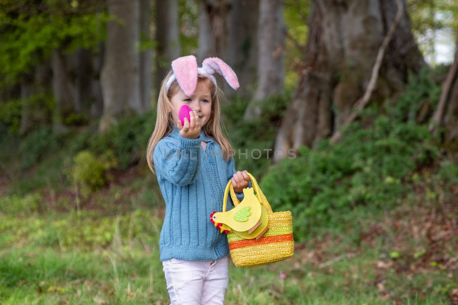 Girl with bunny ears collects the eggs in a basket for Easter