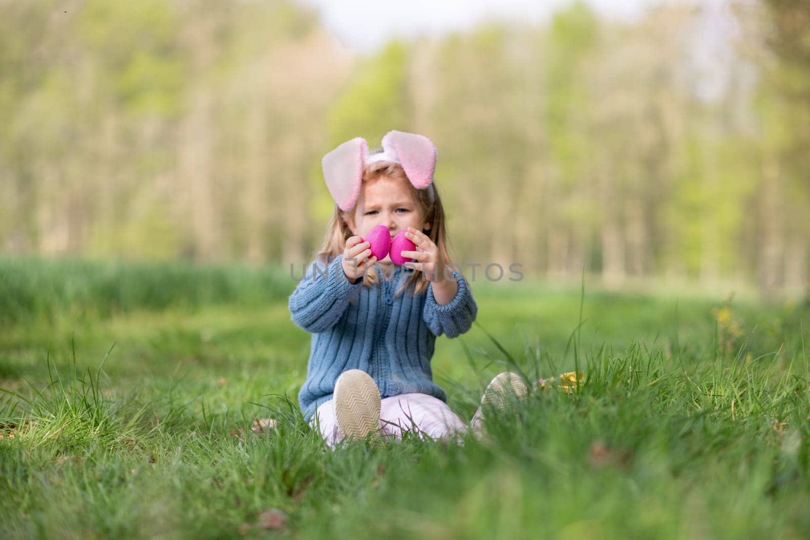 Girl with bunny ears collects the eggs in a basket for Easter