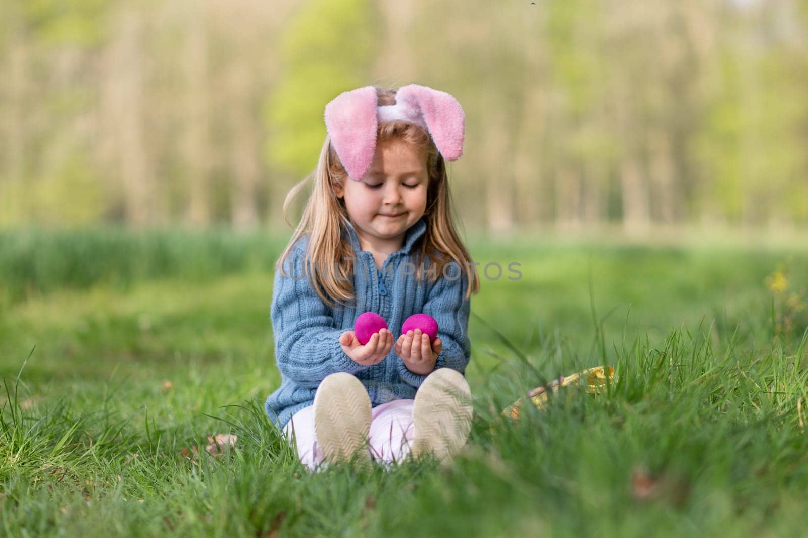 Girl with bunny ears collects the eggs in a basket for Easter