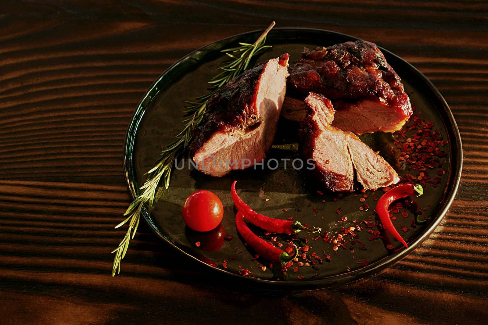 Prepared meat with pepper and rosemary on a wooden table in contrast light by berezko