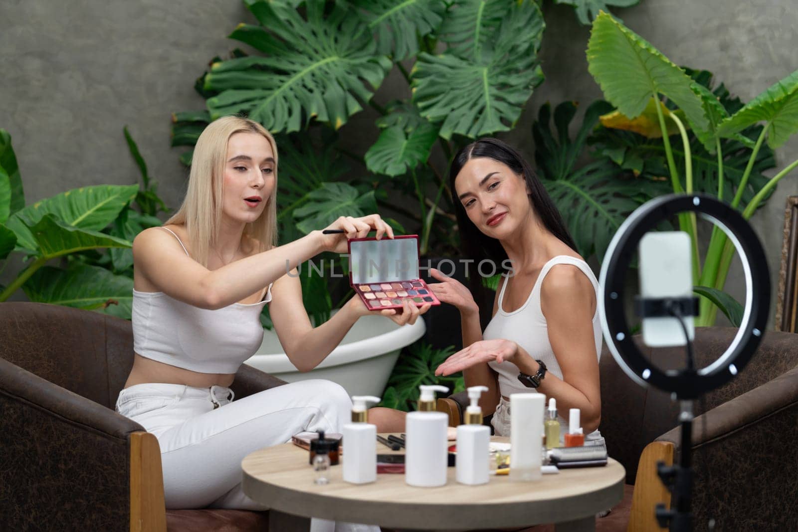 Two beautiful content creator making natural beauty and cosmetic tutorial on green plant garden video. Beauty blogger showing how to beauty care to social medial audience using selfie stick . Blithe