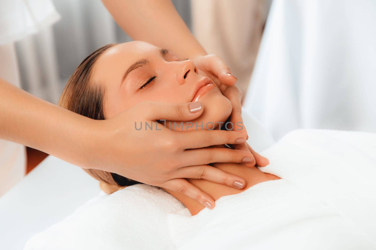 Caucasian woman enjoying relaxing anti-stress head massage and pampering facial beauty skin recreation leisure in dayspa modern light ambient at luxury resort or hotel spa salon. Quiescent